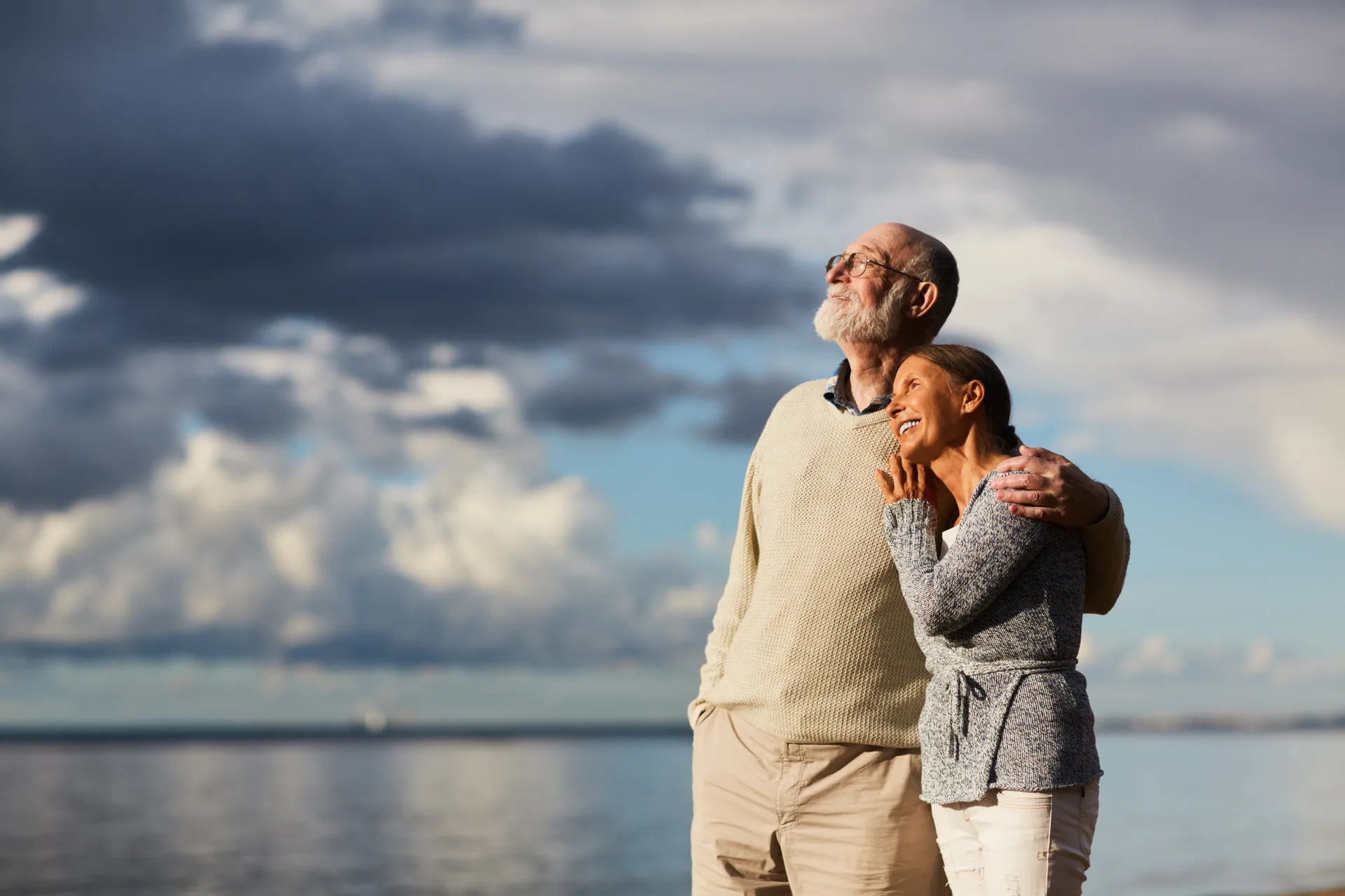 An older couple standing together looking out over the sea